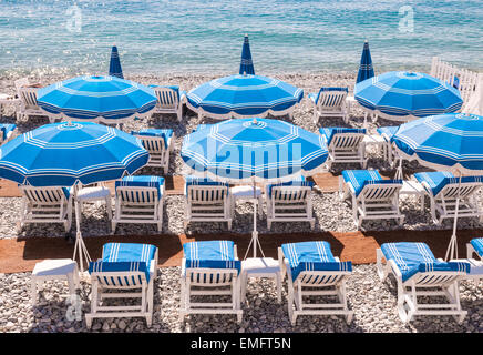Blue ombrelloni e sdraio sulla spiaggia di ciottoli di Nizza, Francia. Foto Stock