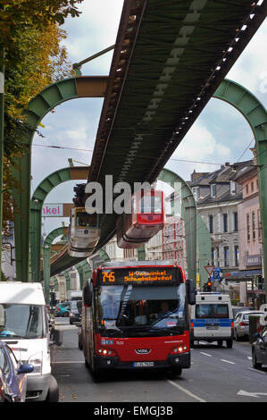 Treno articolato, schwebebahn, ferrovia sospesa, al di sopra di un bus sul Vohwinkeler Strasse, Wuppertal, Renania settentrionale-Vestfalia, Germania Foto Stock