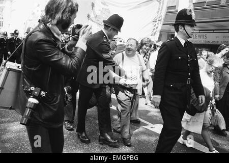 Un uomo è delicatamente restarined da un poliziotto con un colpetto sul suo stomaco come centinaia di lavoratori siderurgici hanno marciato attraverso il Park Lane sul loro modo ad un incontro presso la Central Hall di Westminster. Essi sono stati staging a salvare i nostri posti di lavoro protesta. Il 19 maggio 1975. Foto Stock