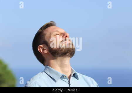 L'uomo respirazione profonda aria fresca all'aperto e con un cielo blu in background Foto Stock