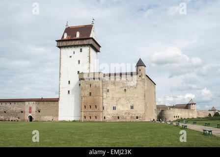 Hermanns castello nella città di Narva in Estonia. Un castello in pietra e una grande torre di bianco con un tetto. Cielo nuvoloso ed erba verde. Foto Stock
