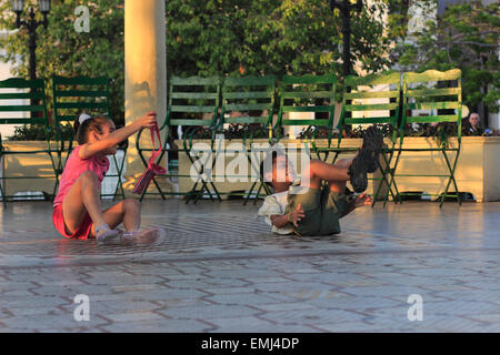 Giovani bambini cubani i ragazzi e le ragazze a giocare sulla fascia stand in Jose Marti Park Cienfuegos Cuba Foto Stock