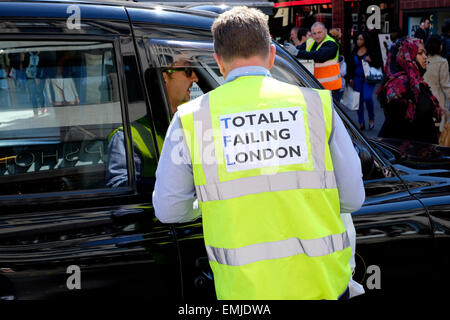 Un black cab driver indossare una divisa da lavoro ad alta visibilità la lettura ' totalmente in mancanza di Londra' in riferimento al trasporto per Londra Foto Stock