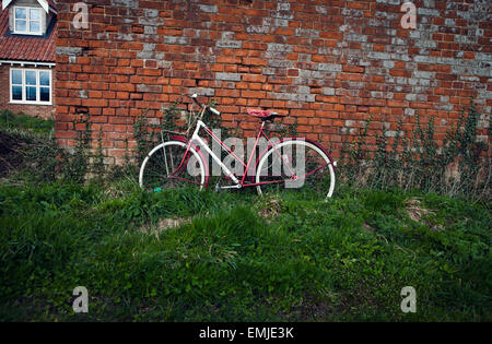 Red bike pendente rosso contro un muro di mattoni Foto Stock