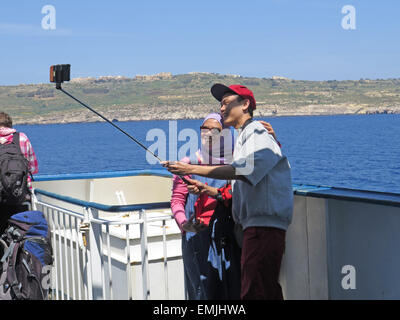 Oriental coppia in vacanza prendendo un selfie su un traghetto per Gozo, Malta Foto Stock