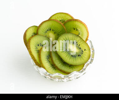 Una ciotola riempita con fette di kiwi su un plastico bianco tavolo. Foto Stock