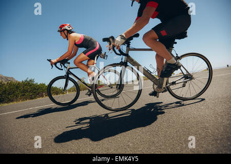 Azione girato di un racing ciclisti. Ciclista equitazione biciclette in discesa sulla strada di campagna. La pratica per la concorrenza. Foto Stock