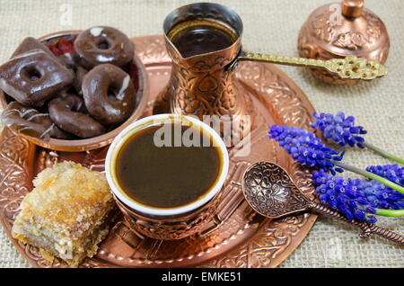 Caffè alla turca con biscotti e fiori in coppe di rame su una piastra Foto Stock