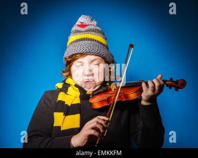 I capelli rossi espressivo ragazzo adolescente suona il violino, funny concetto, isolato su blu Foto Stock