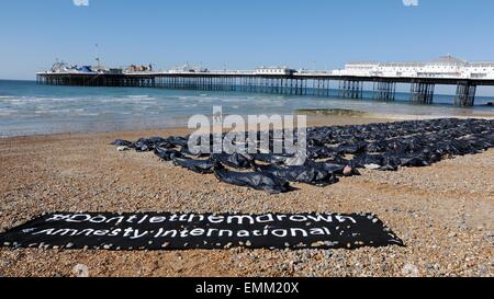 Brighton, Regno Unito. Il 22 aprile, 2015. I membri di Amnesty giacciono nel body bags sulla spiaggia di Brighton questa mattina per evidenziare il crescente problema dei migranti nel Mediterraneo Credito: Simon Dack/Alamy Live News Foto Stock