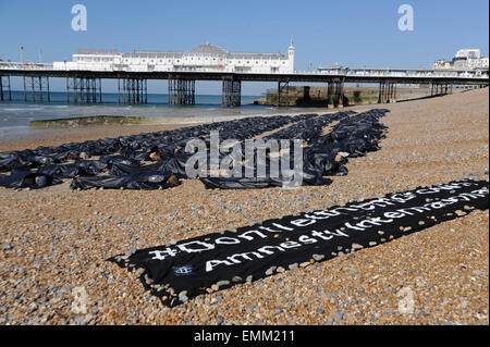 Brighton, Regno Unito. Il 22 aprile, 2015. I membri di Amnesty giacciono nel body bags sulla spiaggia di Brighton questa mattina per evidenziare il crescente problema dei migranti nel Mediterraneo Credito: Simon Dack/Alamy Live News Foto Stock