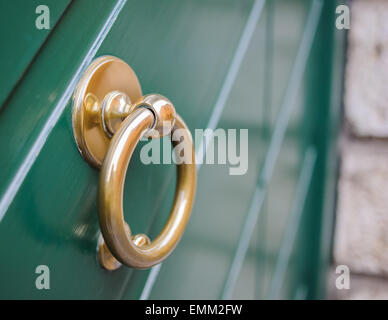 Respingente anello di ottone su una porta di legno di colore verde Foto Stock