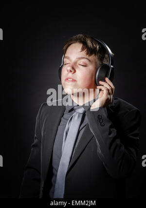 Ragazzo adolescente ascoltando la musica nelle cuffie isolato su sfondo nero Foto Stock