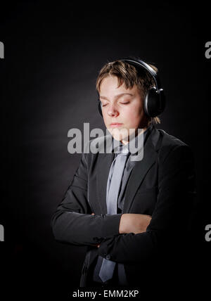 Ragazzo adolescente ascoltando la musica nelle cuffie isolato su sfondo nero Foto Stock