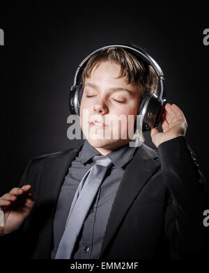 Ragazzo adolescente ascoltando la musica nelle cuffie isolato su sfondo nero Foto Stock