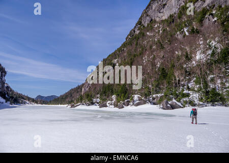 L'uomo trekking attraverso il lago di valanghe nelle Montagne Adirondack, New York Foto Stock