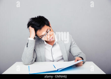 Imprenditore seduti a tavola e leggere documenti di office Foto Stock