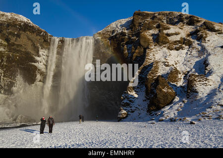 Ai turisti di ammirare la cascata Skogafoss in Islanda durante la breve giornata invernale Foto Stock