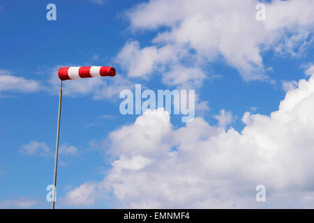 Immagine di un rosso bianco banderuola contro il cielo blu con nuvole bianche Foto Stock
