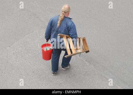 Lavoratore stanco che porta un secchio e una scala. Foto Stock