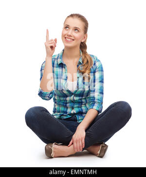 Sorridente giovane donna puntare il dito fino Foto Stock