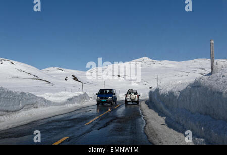 Guida auto in direzione est sulla strada E7 su Hardangervidda, Norvegia, con alte mura di neve che circonda la strada. Foto Stock