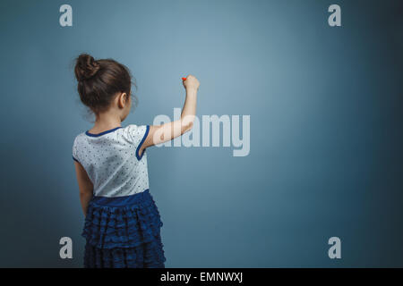 Una bambina di sette anni aspetto europeo brunette scrive vista posteriore su sfondo grigio Foto Stock