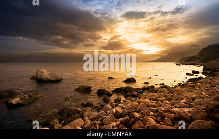 Bel tramonto sulle rocce in riva al mare Foto Stock