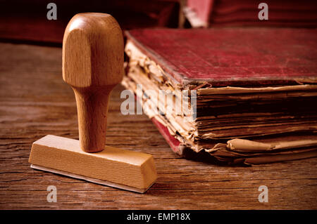 Primo piano di un timbro di gomma e un usurati vecchio libro, su una tavola in legno rustico Foto Stock