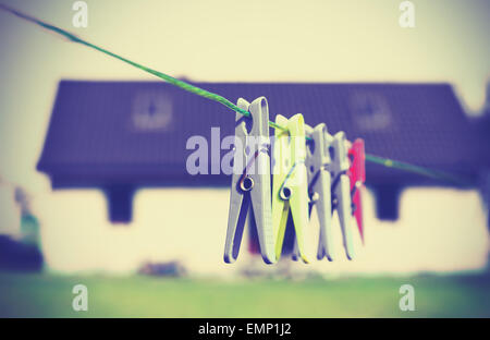 Retrò clothespins filtrato appeso a una fune nella parte anteriore della casa, concetto foto. Foto Stock