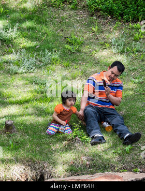 Un padre ispanica scatta foto con il suo telefono cellulare di sua figlia piccola in un parco pubblico. Oklahoma, Stati Uniti d'America Foto Stock