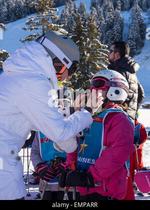 La madre e il bambino piccolo in sci vestiti preparando per una lezione di sci con pendenza dietro Foto Stock