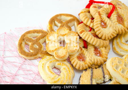 Mazzetto di tè cookies legate con un nastro rosso appendere insieme su bianco Foto Stock