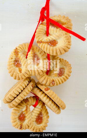 Mazzetto di tè cookies legate con un nastro rosso appendere insieme su bianco Foto Stock