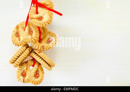 Mazzetto di tè cookies legate con un nastro rosso appendere insieme su bianco Foto Stock