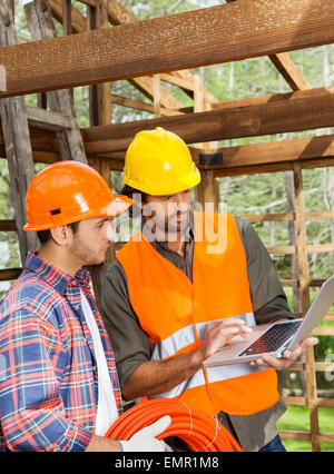 Gli architetti utilizzano il portatile in sito in costruzione Foto Stock