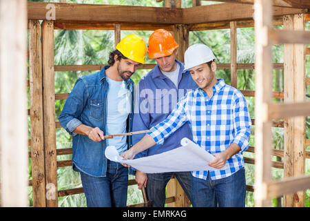Architetti discutendo su blueprint presso il sito Foto Stock