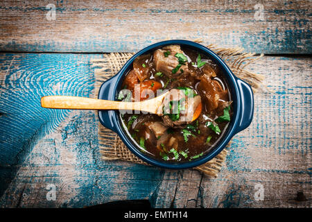 Spezzatino di carne con verdure ed erbe sul vecchio tavolo in legno Foto Stock