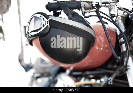 Un casco vintage e occhiali appeso al manubrio di una custom motocicletta in corrispondenza di un rally in California. Foto Stock