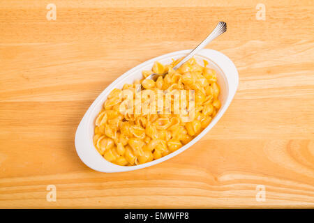 Un bianco piatto di maccheroni e formaggio con la forcella sulla tavola di legno Foto Stock