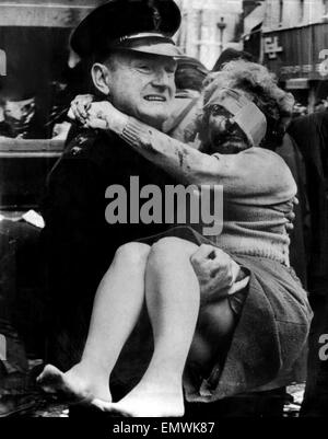 Un ispettore RUC porta un ferito le donne dalla galleria di negozi in Donegall Street, Belfast, dopo una bomba dell'IRA è andato fuori. Xx Marzo 1972. Foto Stock