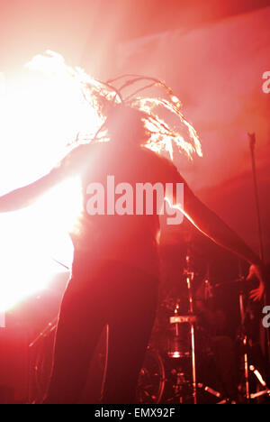 Vista posteriore di un anonimo o anonimi rock star sul palco, saltando e piena di energia, circondato da red illuminazione scenica. Foto Stock