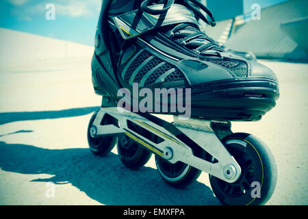Primo piano dei piedi di un giovane uomo di pattinaggio con pattini a rotelle in linea, con una piccola aggiunta di vignette Foto Stock