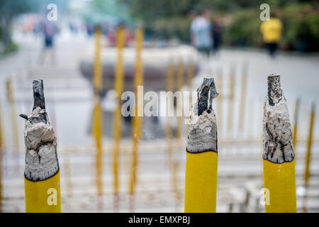 Tre grandi bastoni di incenso bruciare nel tempio cinese con persone sfocate in background Foto Stock