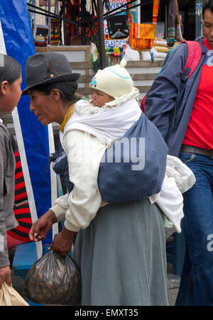 Donna con bambino shopping al mercato di Otavalo, Ecuador Foto Stock