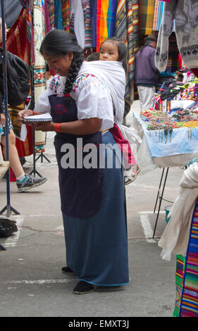 Donna con bambino vendere al mercato di Otavalo, Ecuador Foto Stock