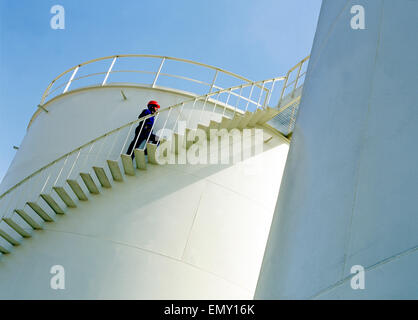 Un lavoratore arrampicata serbatoio di accumulo di olio scale Foto Stock