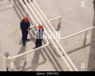 Vista aerea di due raffinerie di petrolio di lavoratori in discussione tra le tubazioni. Foto Stock