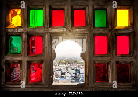 Vista sulla città dal colorato mosaico finestra nel City Palace Museum di Udaipur, Rajasthan, India Foto Stock