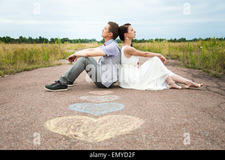 Sposi seduti sul terreno. amore simboli sulla pavimentazione. cuori. persone nell'amore. Felice sposa e lo sposo ritratti Foto Stock
